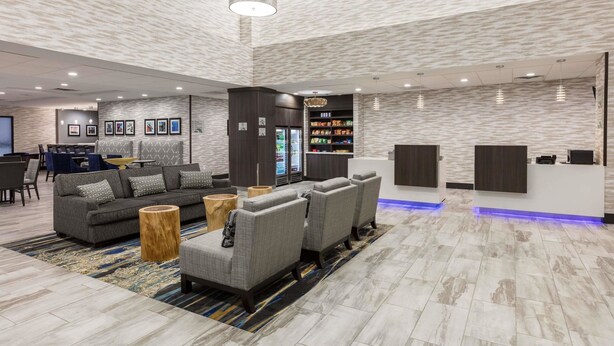 En moderne lobby med sofaer, stole, en receptionsdisk og et snackområde.