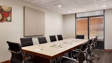 A conference room with a long table, black chairs, and a whiteboard.