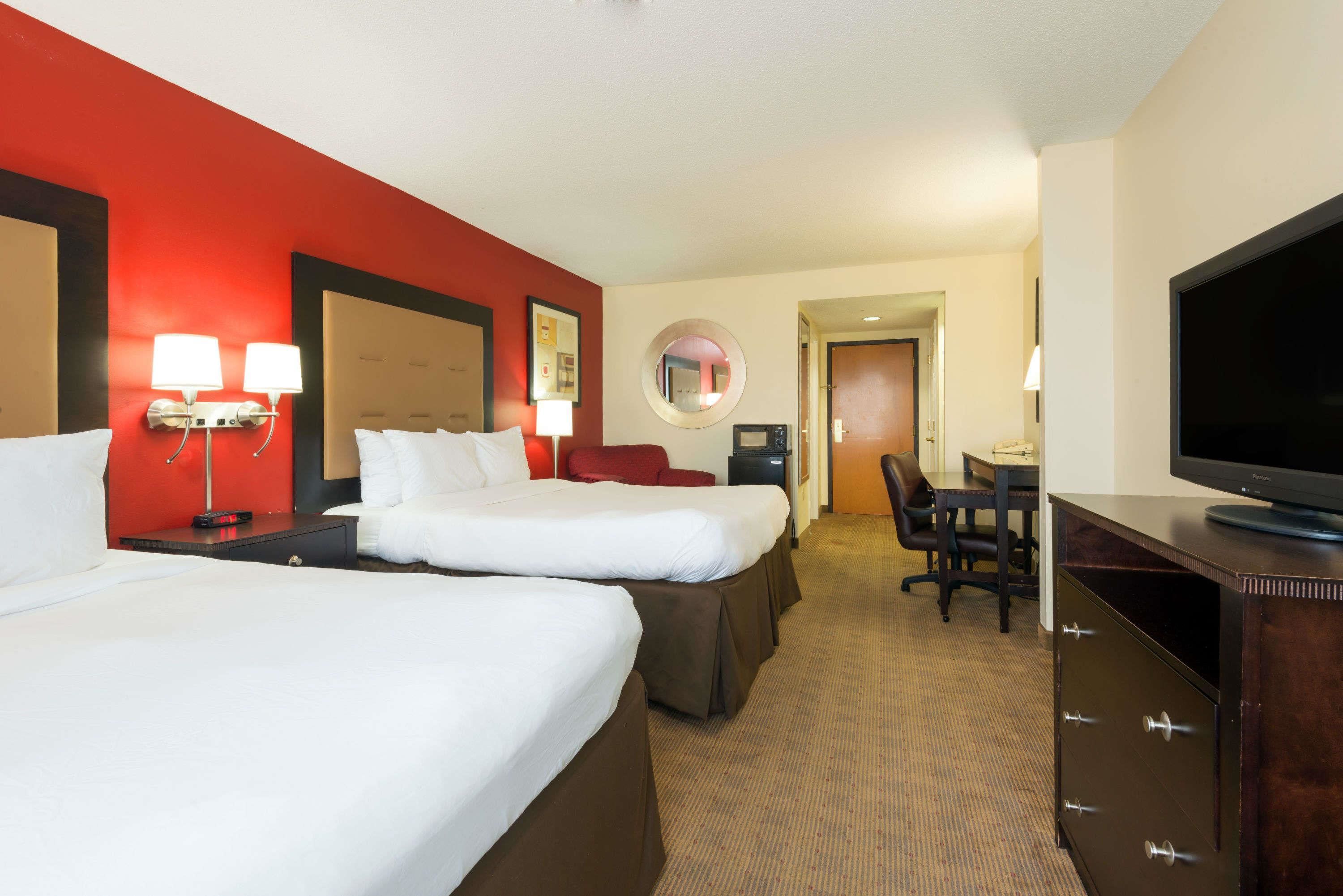 Une chambre d’hôtel avec deux lits, un bureau, une télévision et un miroir.