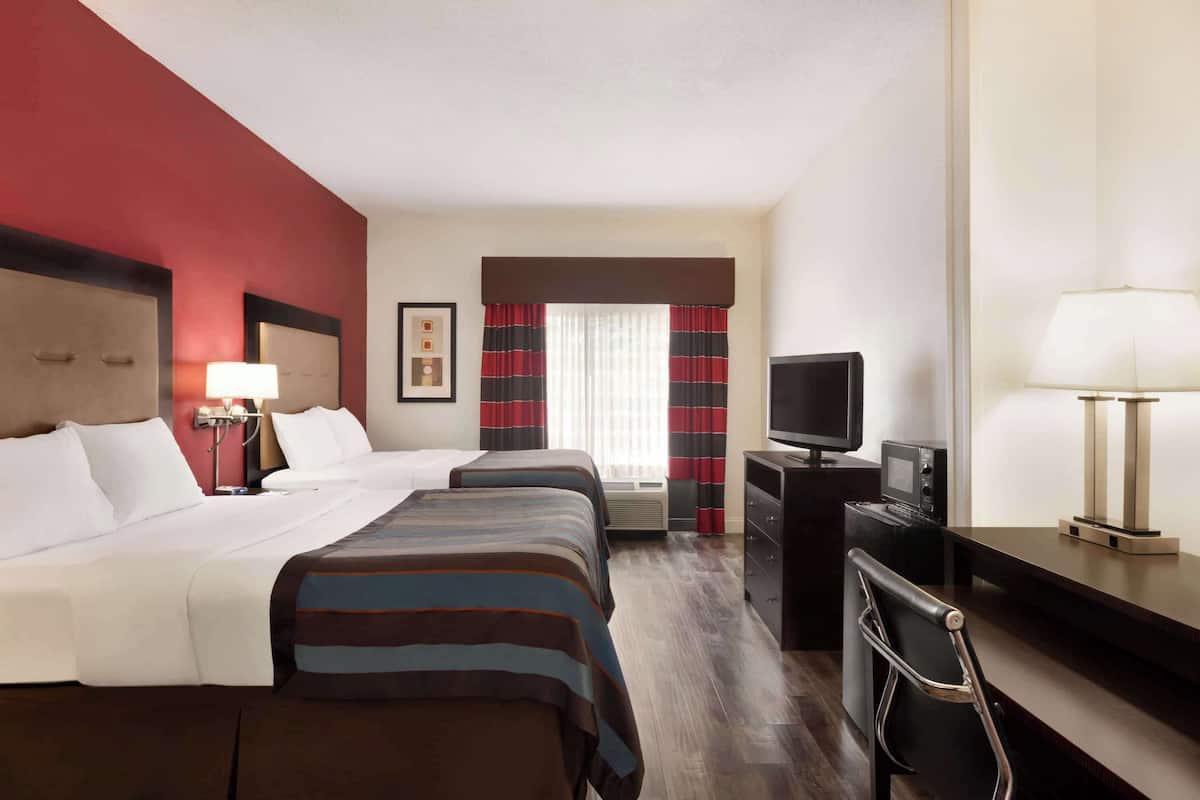 A hotel room with two beds, a TV, a desk, and a chair.