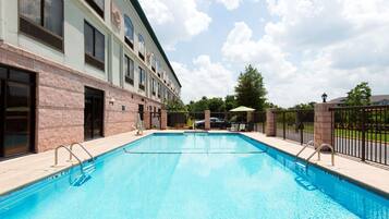 A swimming pool adjacent to a building with a brick facade and multiple windows.