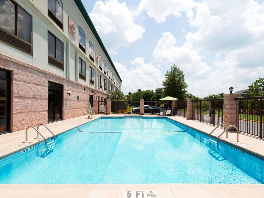 A swimming pool adjacent to a building with a brick facade and multiple windows.