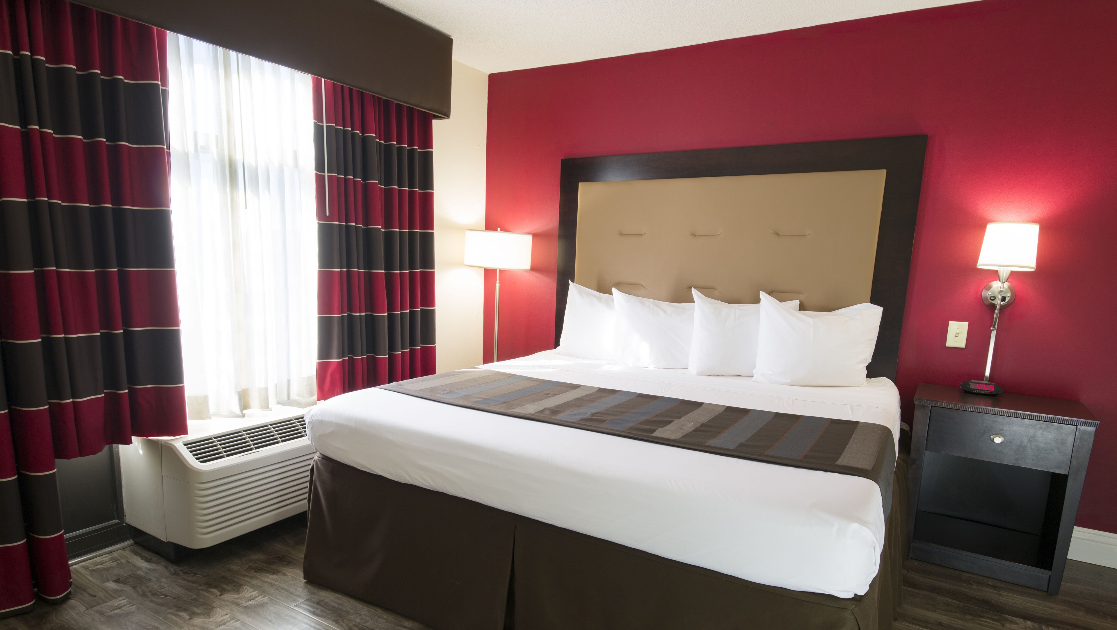 Ein Hotelzimmer mit einem großen Bett, zwei Nachttischlampen, einem Heizgerät und einem Nachttisch mit Lampe.