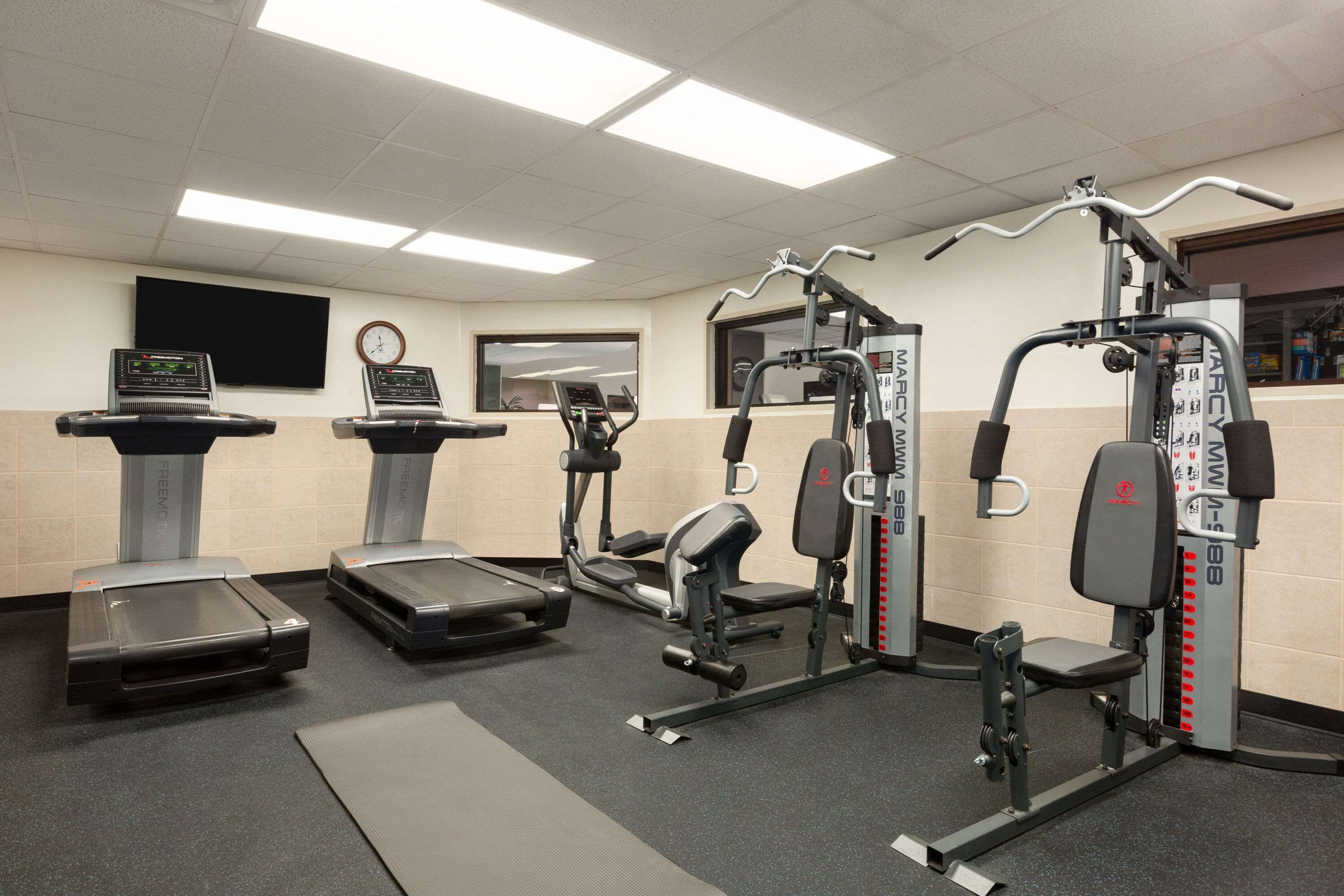 A gym with treadmills, elliptical machines, and weightlifting equipment.