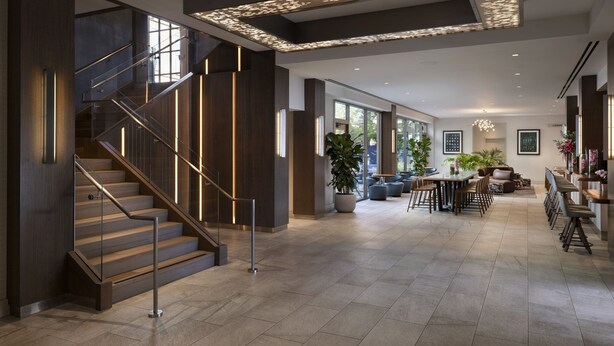 Un interior espacioso con una escalera, una zona de comedor y un gran ventanal que proporciona luz natural.