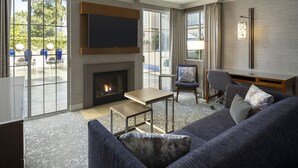 Una sala de estar moderna con chimenea, zona de estar y ventanas amplias con vistas al exterior.