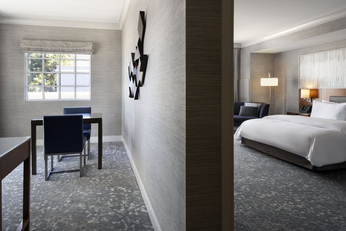 A hotel room with a bed, a desk, and a chair.