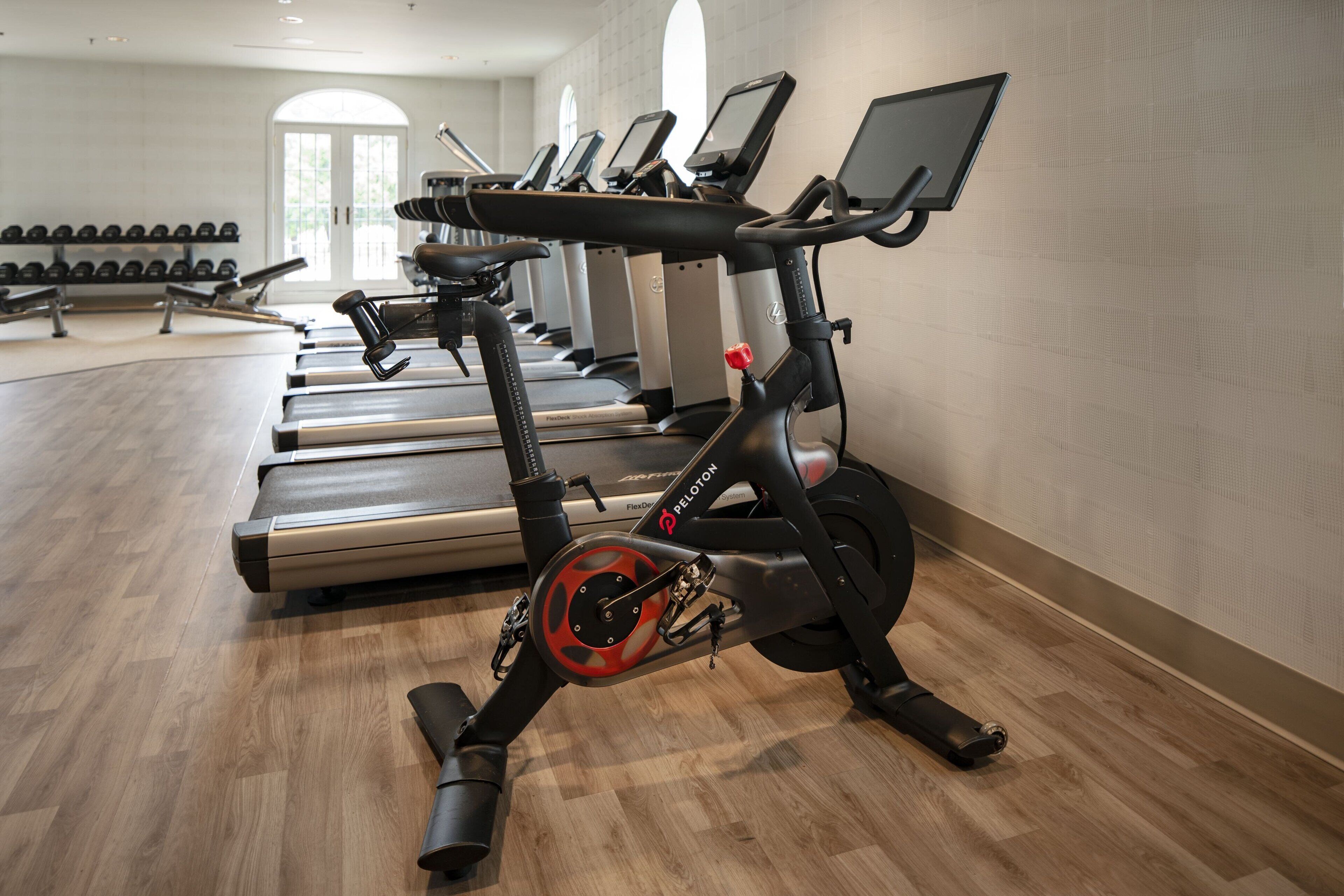 Une salle de sport équipée de vélos d’appartement, de tapis de course et d’haltères.