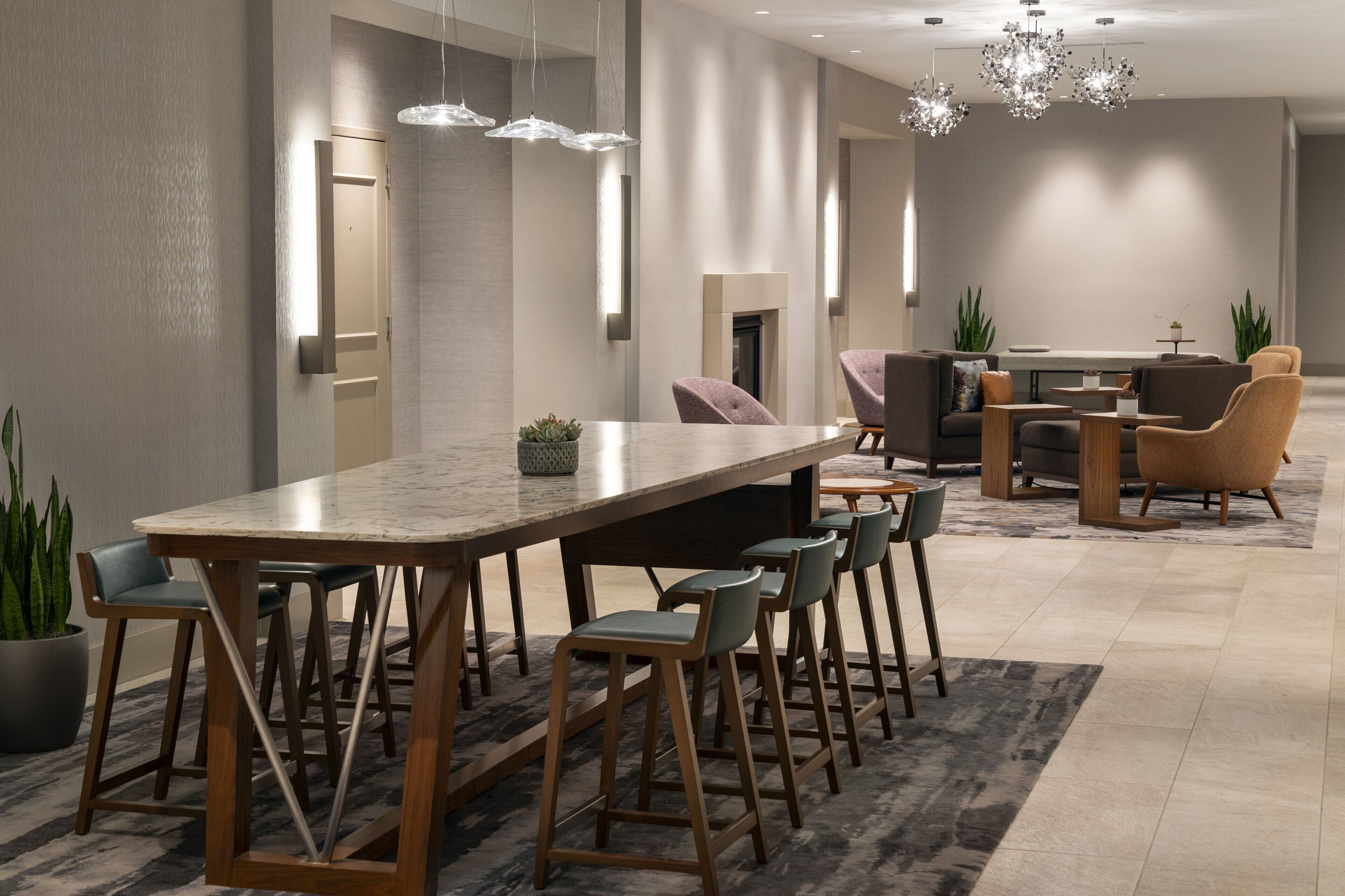 Um hall de hotel moderno com um balcão longo, área de estar e lareira.