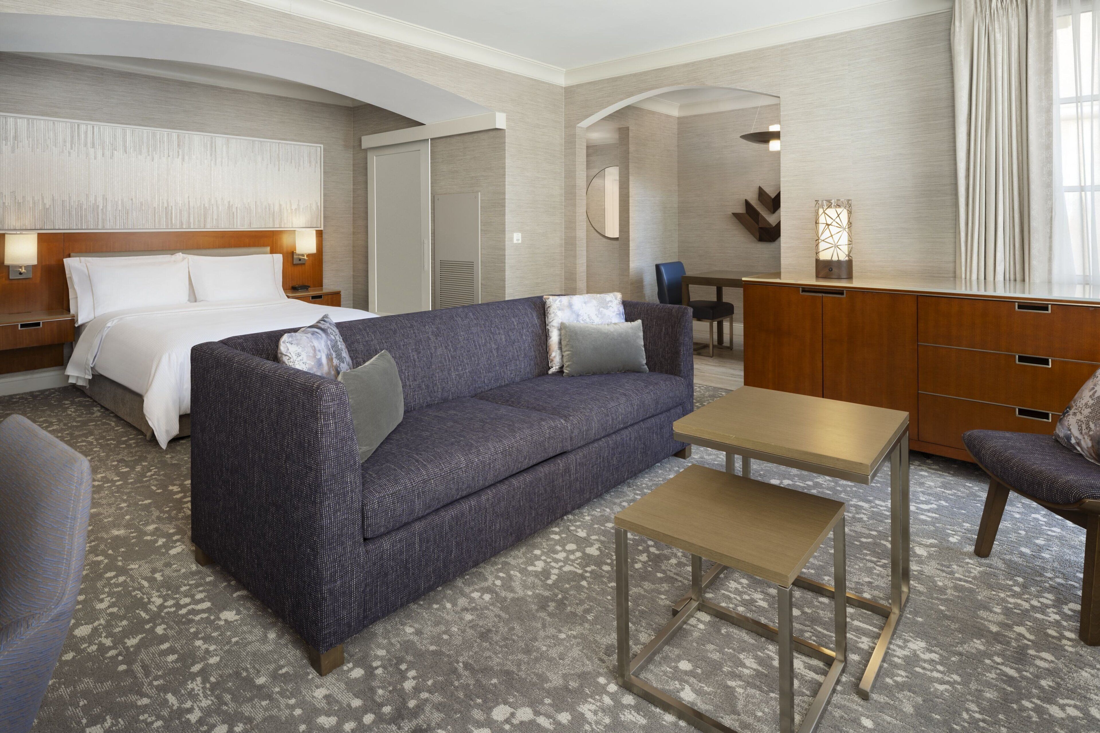 Een hotelkamer met een bed, een bank, een bijzettafeltje en een bureau.