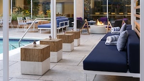 Un área de lounge exterior moderna con asientos, piscina y una chimenea.