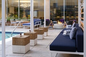 A modern outdoor lounge area with seating, a pool, and a fire feature.