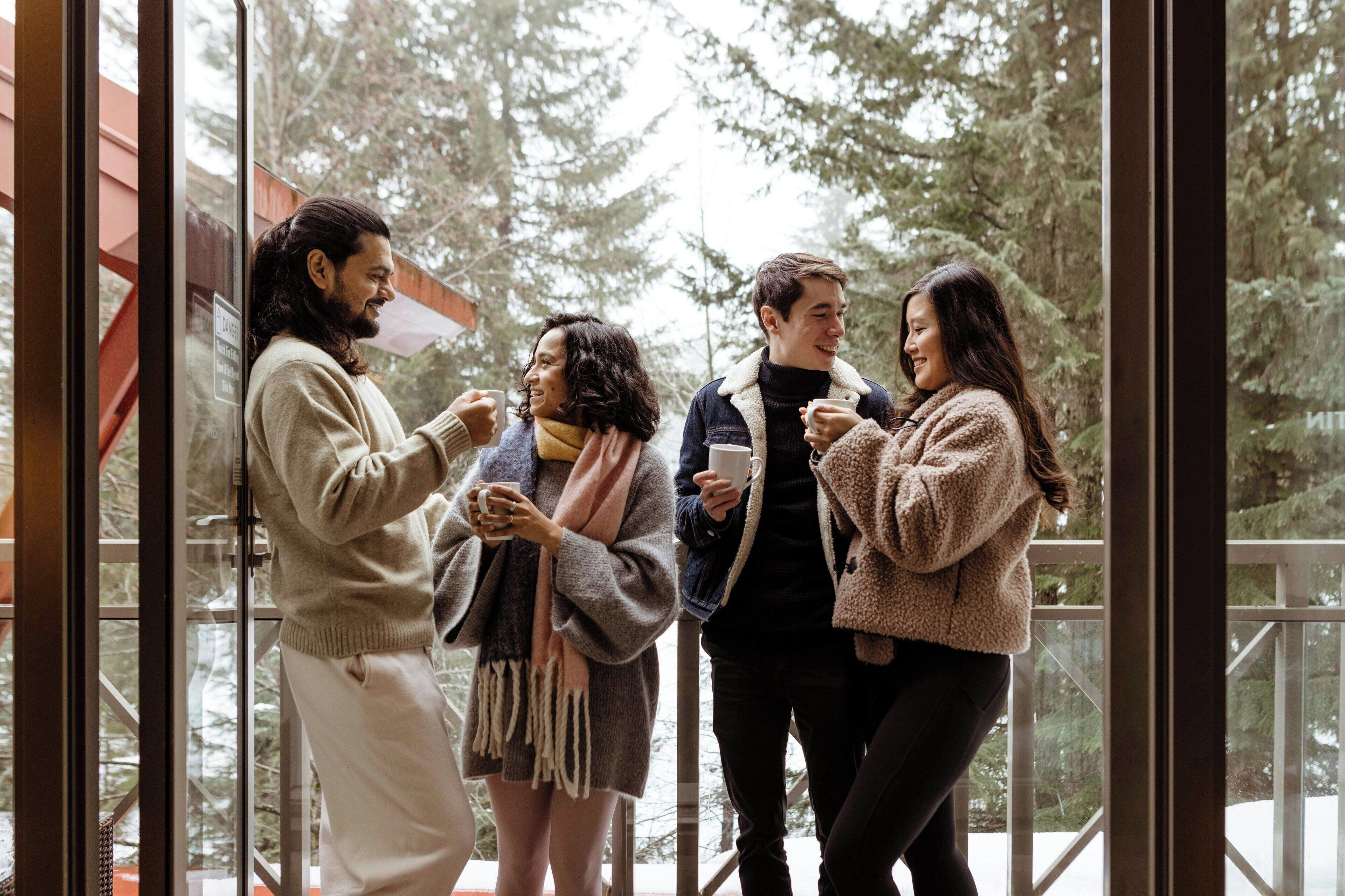 A group of people standing on a balcony with a view of trees and a red structure in the background.