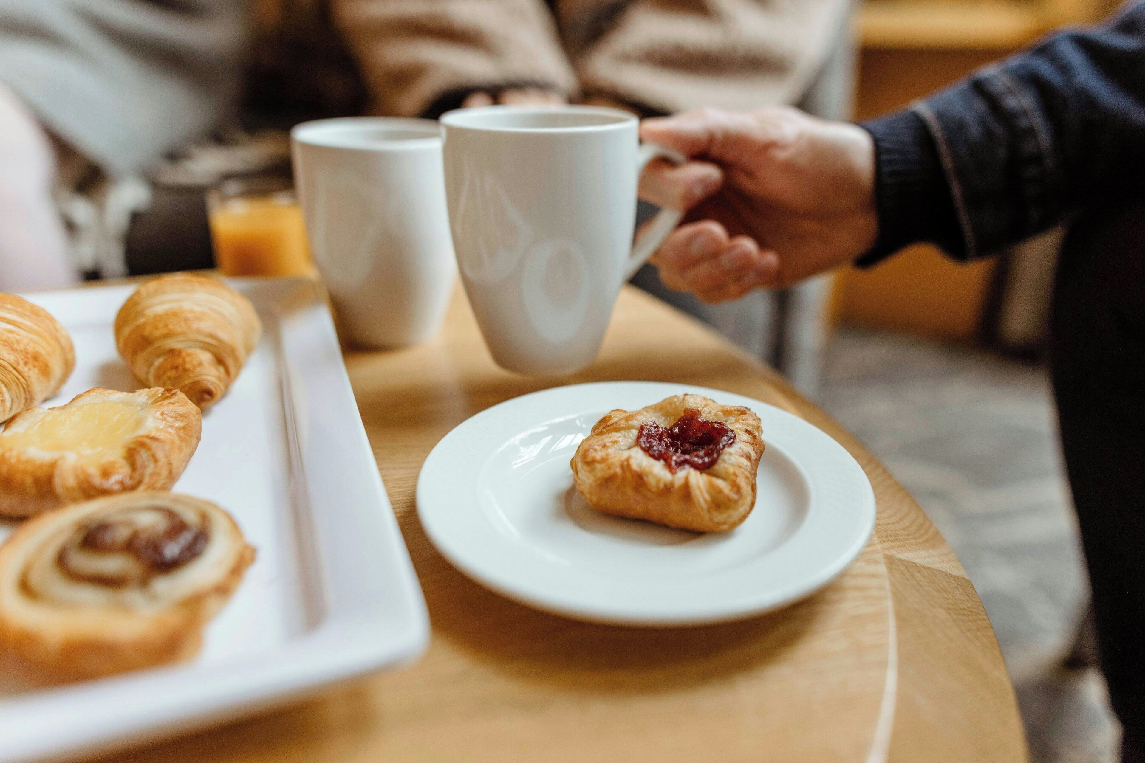 A breakfast setting with pastries and coffee cups on a table.