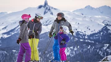 A group of skiers on a snowy mountain with a clear view of the peaks in the background.