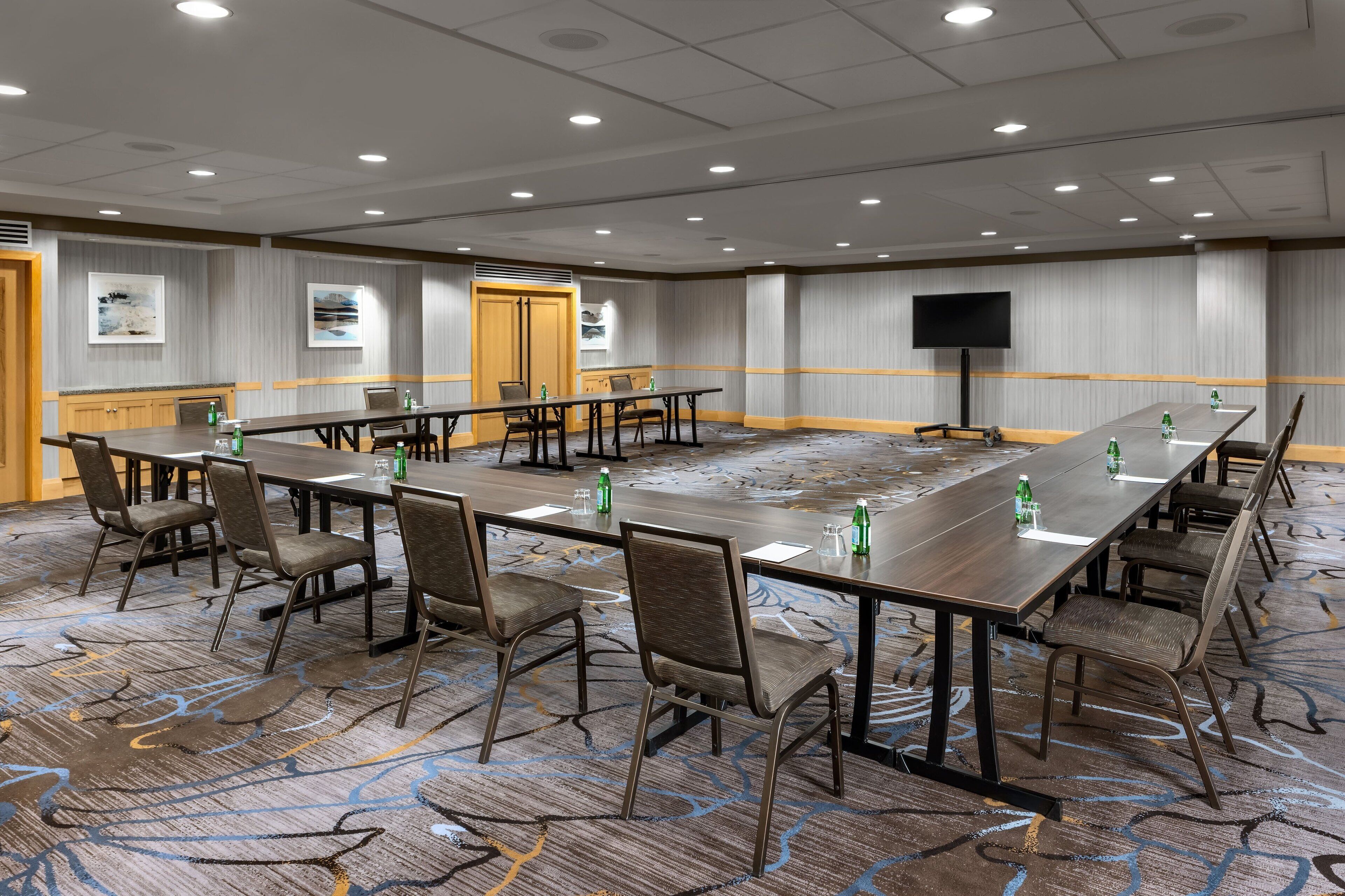 Une salle de conférence équipée de longues tables, de chaises et d’un téléviseur à écran plat.