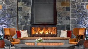 Una sala de estar moderna con una pared de piedra, una chimenea y asientos cómodos.