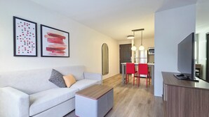 Una sala moderna con un sofá, reposapiés y una zona de comedor con sillas rojas.