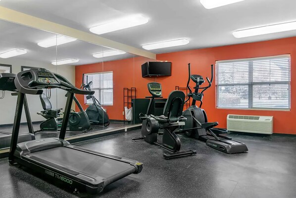 Un gimnasio con cintas de correr, elípticas y equipo de pesas.
