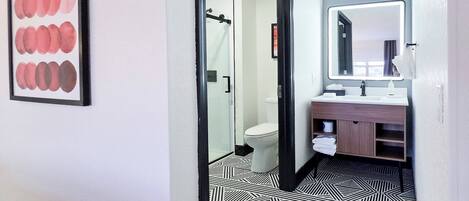 A modern bathroom with a large mirror, a sink, and a toilet.