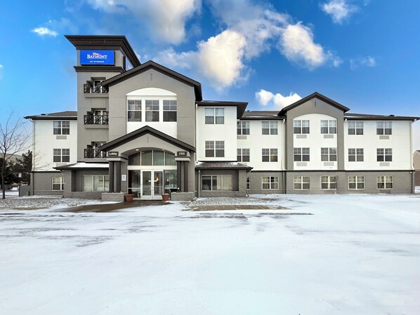 A multi-story hotel with a central lobby, balconies, and a parking lot. - Baymont by Wyndham Auburn Hills South (Auburn Hills)