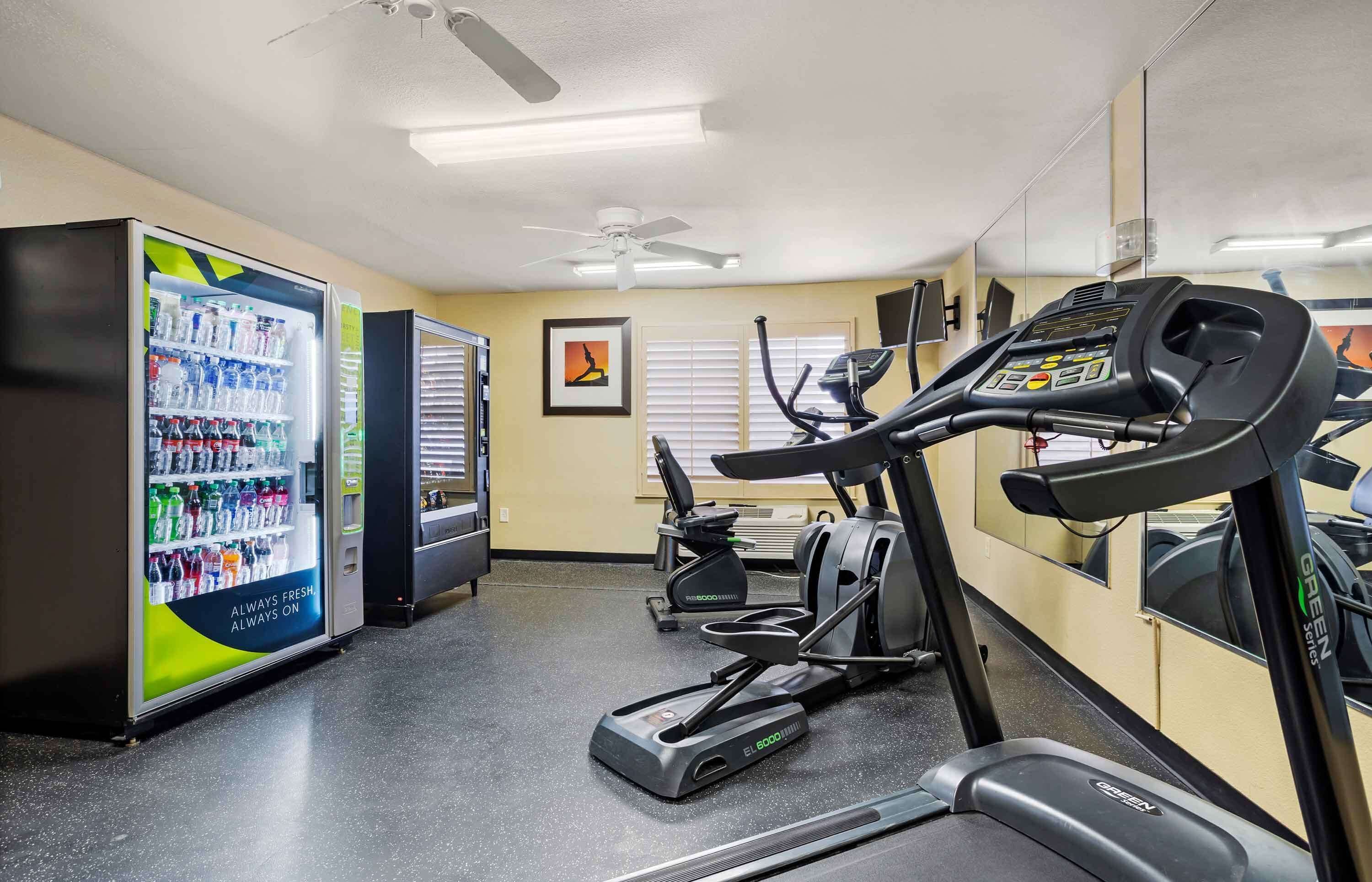 A gym with treadmills, ellipticals, and a water cooler.