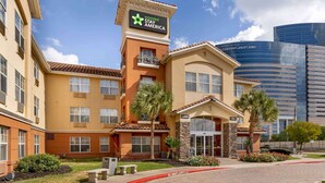 A hotel with a sign for Extended Stay America, a lobby entrance, and a modern building in the background. - Extended Stay America Suites Houston Med Ctr Braeswood Bl (Houston)