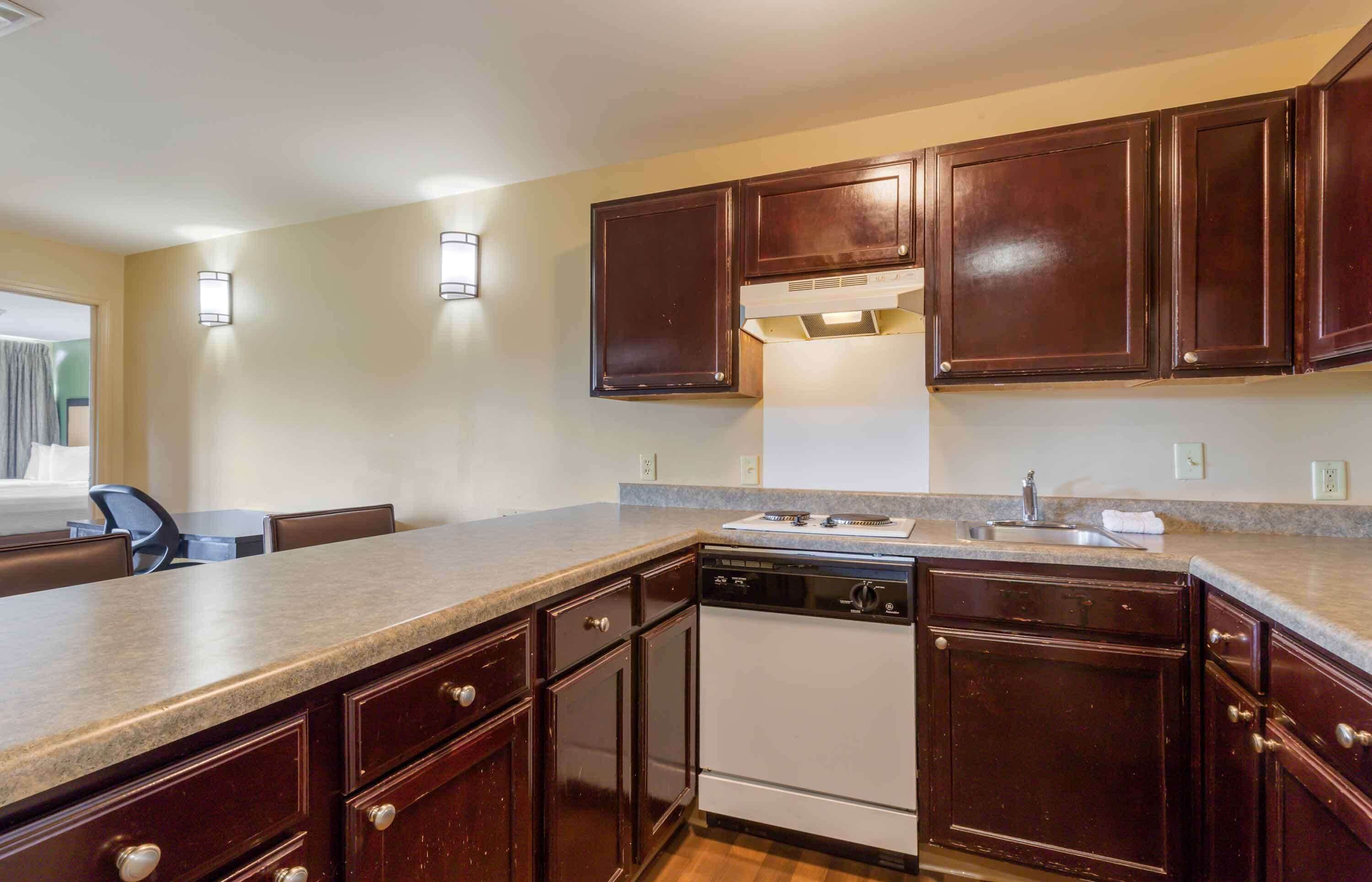 A kitchen with dark wooden cabinets, a white dishwasher, and a granite countertop.