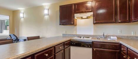A kitchen with dark wooden cabinets, a white dishwasher, and a granite countertop.