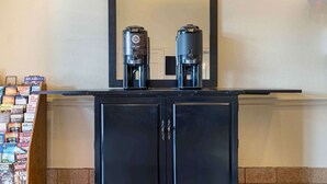 Un meuble noir sur lequel sont posées deux machines à café, un miroir au-dessus et une rangée de livres sur le côté gauche.