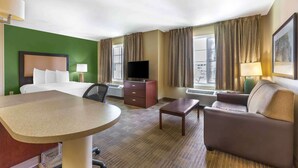 A hotel room with a bed, a desk, a sofa, a TV, and a window with curtains. - Extended Stay America Suites Houston Med Ctr Braeswood Bl (Houston)