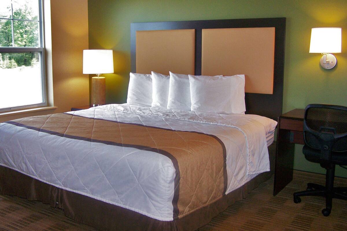 Een hotelkamer met een groot bed, twee bedlampen, een bureau en een stoel.