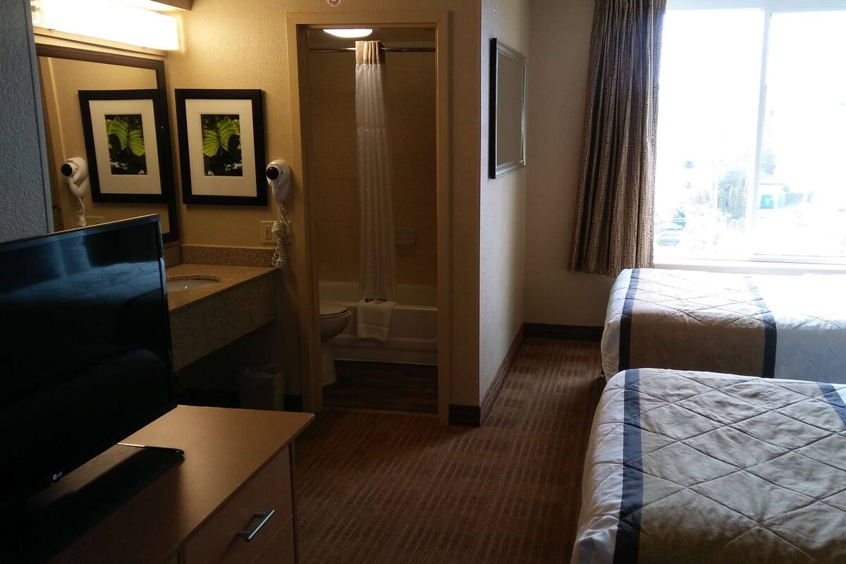 Een hotelkamer met een televisie, bureau, bed en een badkamer.