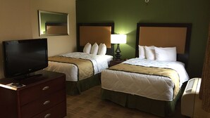 Une chambre d’hôtel avec deux lits, une télévision, une commode et une lampe.