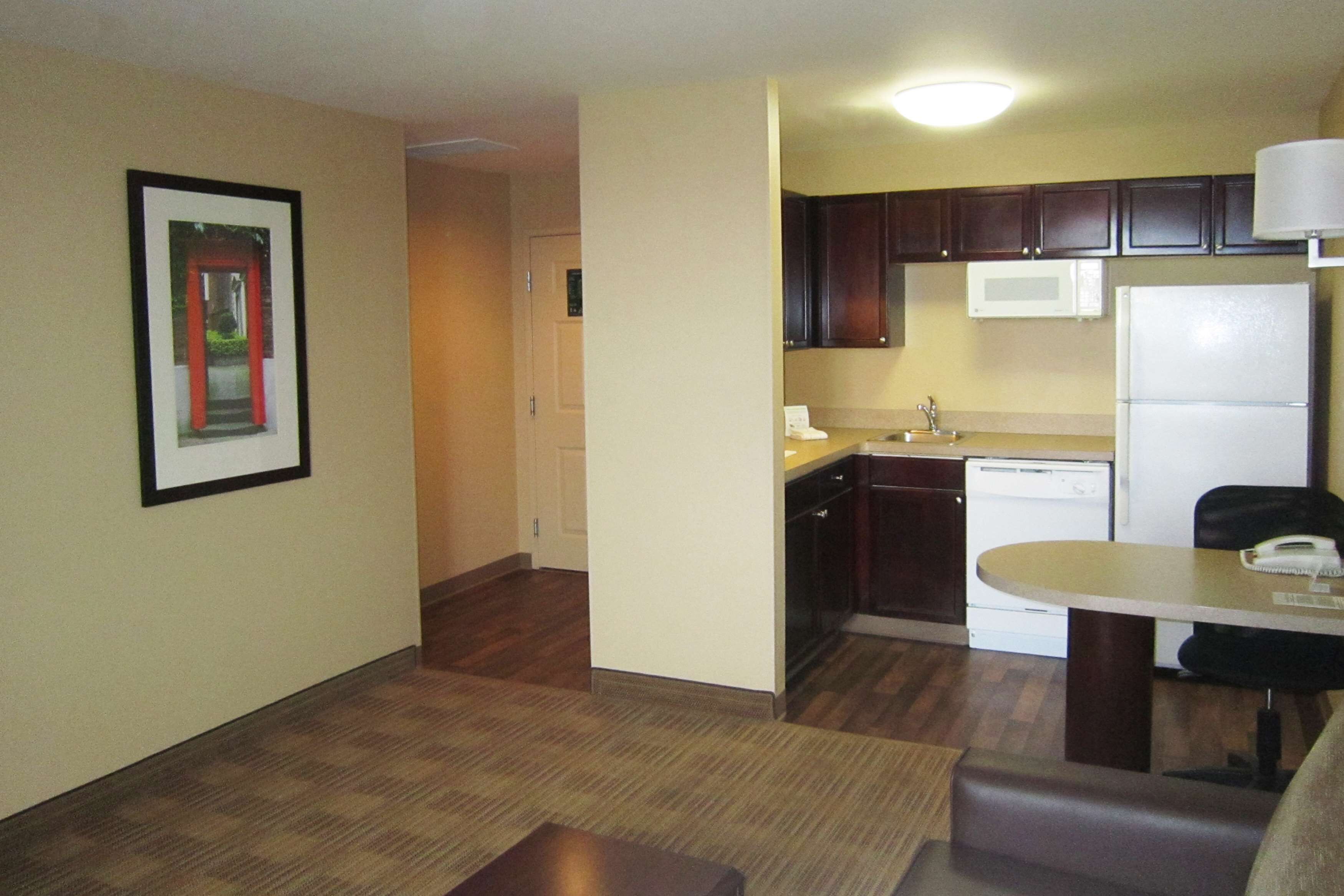 A compact kitchen with dark wooden cabinets, a white refrigerator, and a microwave.