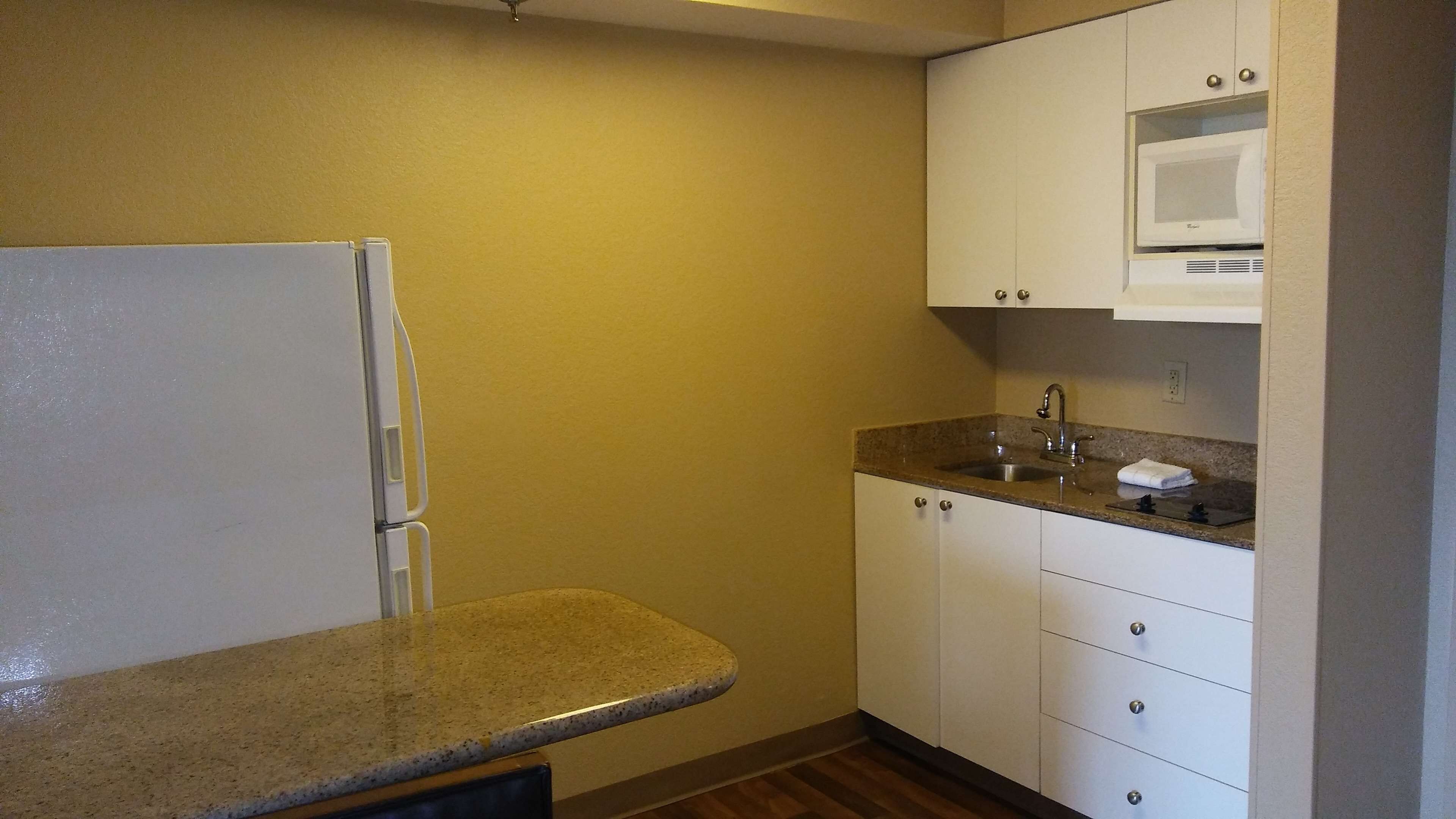 A compact kitchen with a refrigerator, a sink, and a microwave.