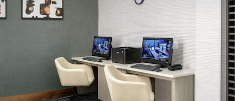 A workspace with two desks, each with a computer and a chair.