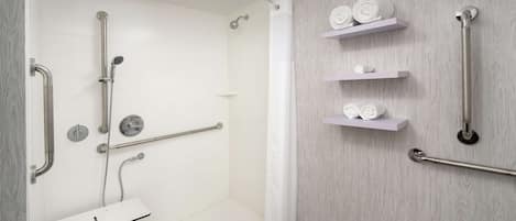 A modern bathroom with a walk-in shower, grab bars, and a white sink.