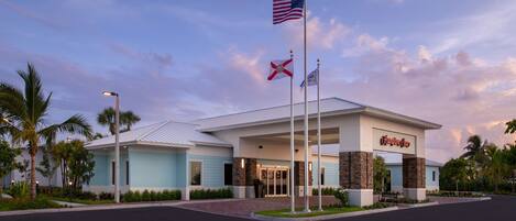 A hotel entrance with a sign reading "Hampton Inn" and flags, including the American flag and a state flag.