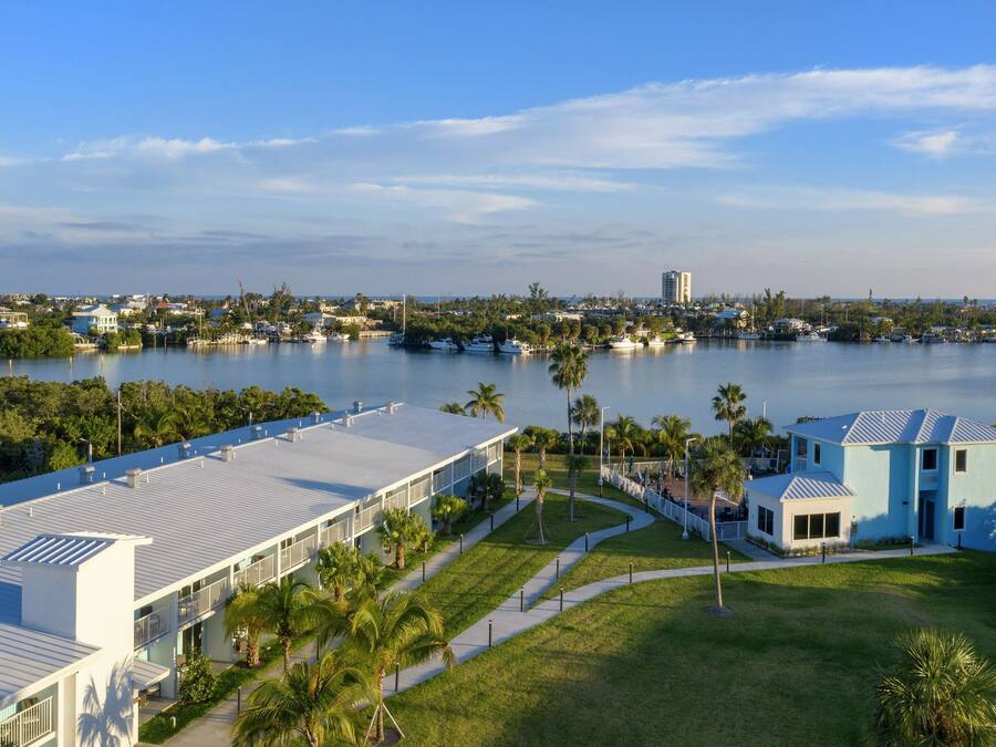 A coastal hotel with a large building, a marina, and a view of the water.