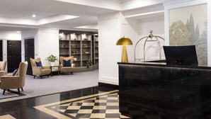A lobby with a reception desk, seating area, and a bookshelf.