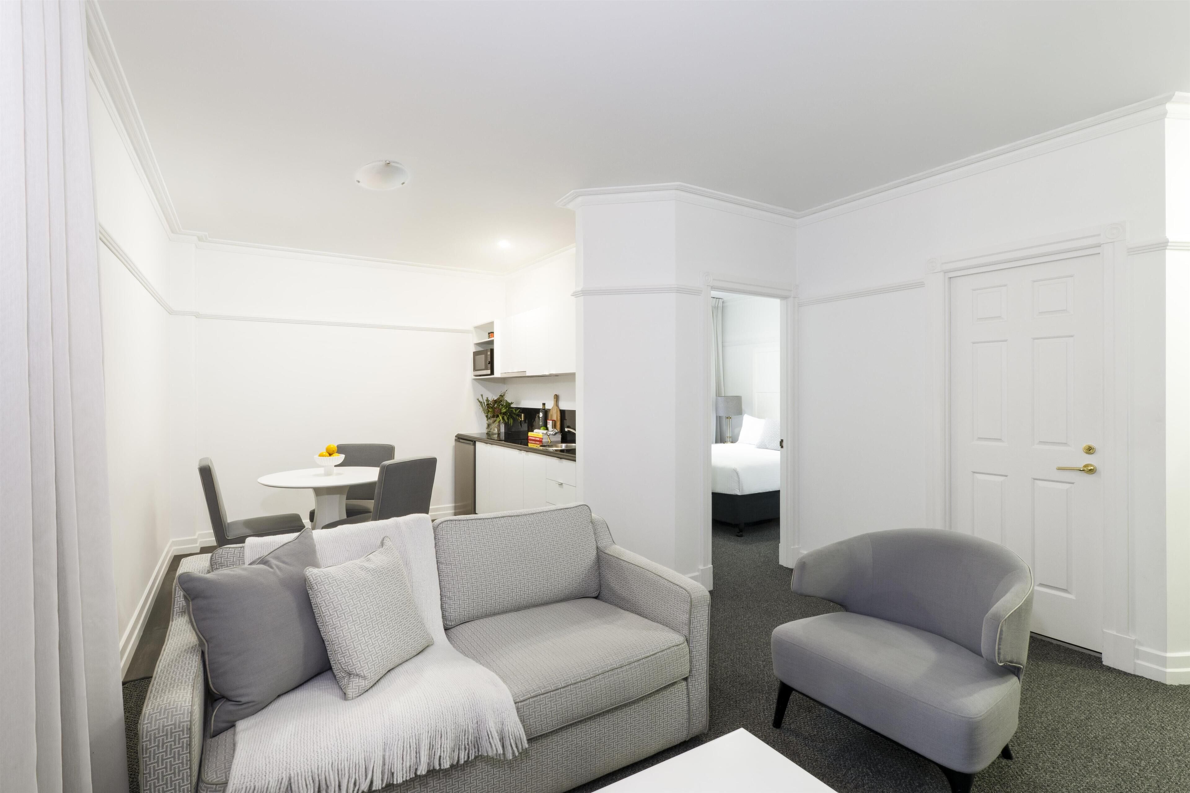 A modern living room with a grey sofa, a grey armchair, and a white coffee table.