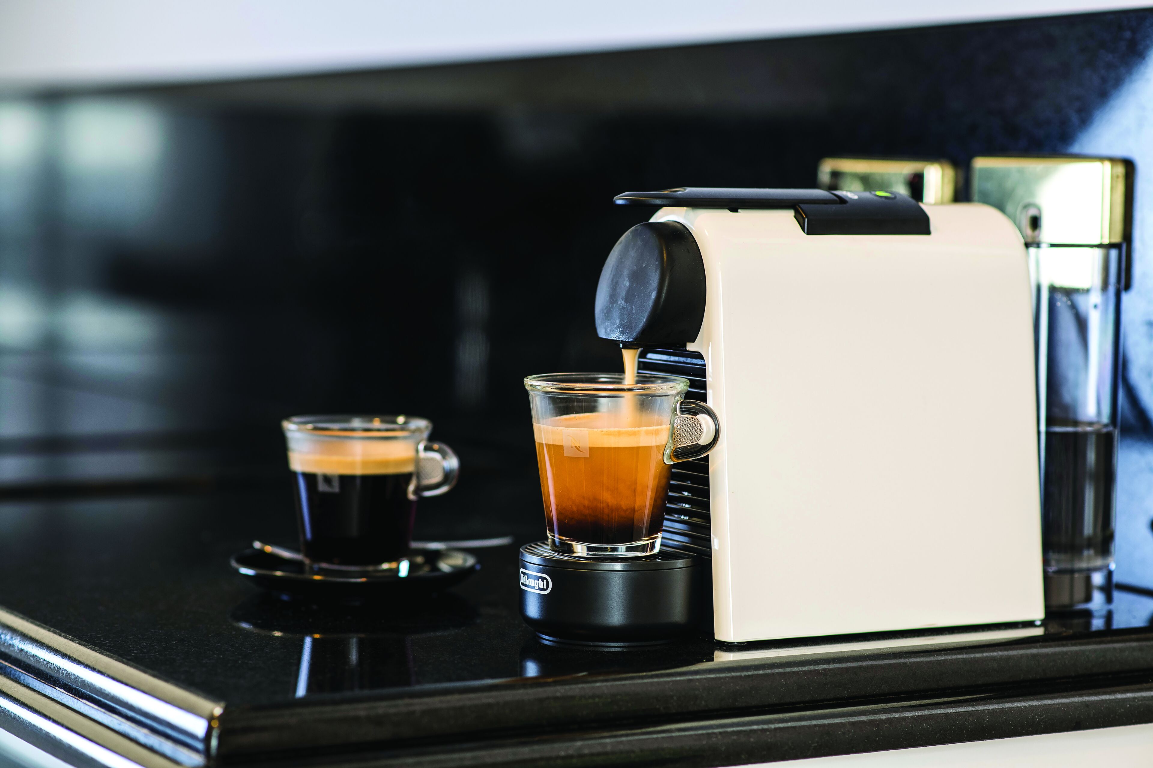 A coffee machine dispensing coffee into two cups on a black countertop.