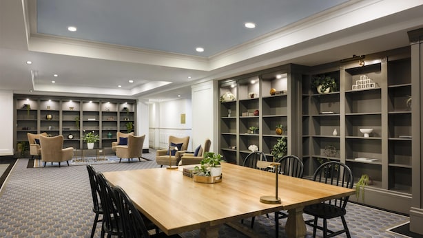 A spacious room with a wooden dining table, multiple chairs, and built-in shelving units filled with decorative items.