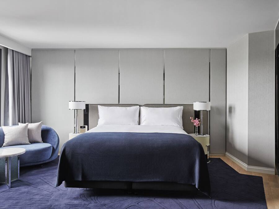 Ett modernt hotellrum med en stor säng, en soffa och ett litet bord.