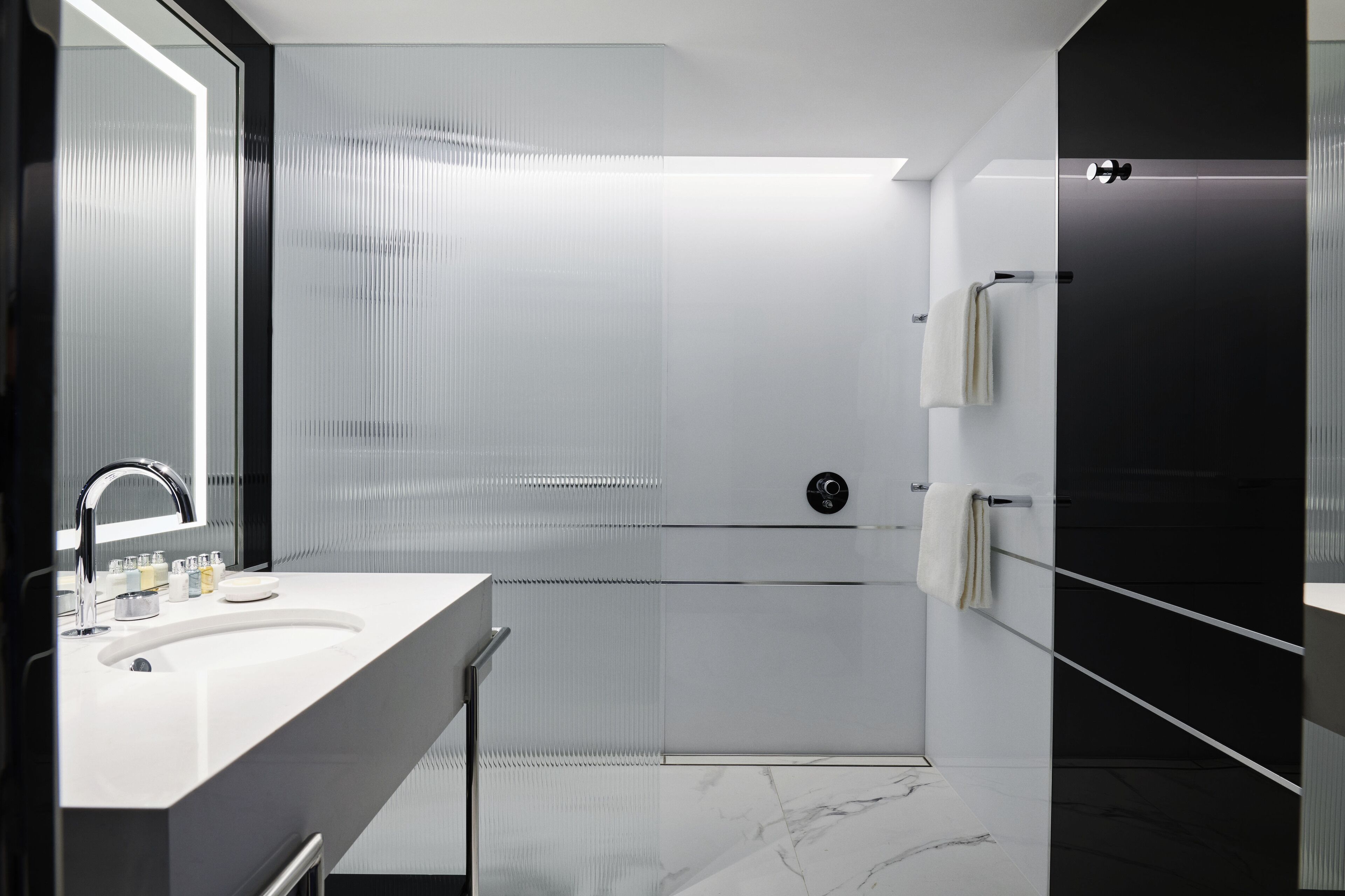 A modern bathroom with a large mirror, a sink, and a shower area.