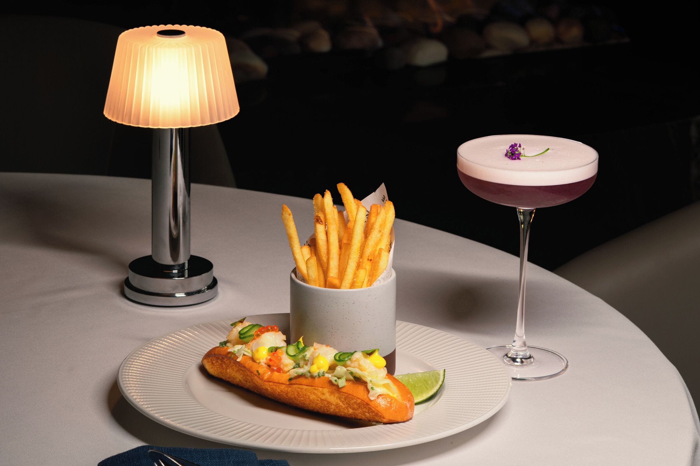 Ein Tisch mit Essen, einem Getränk und einer Lampe.