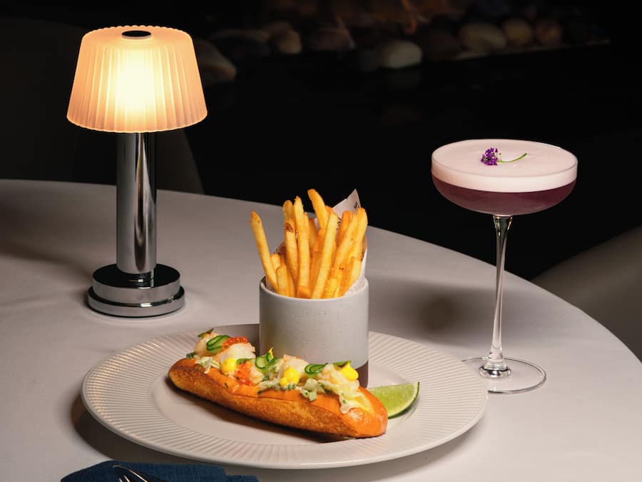 Ein Tisch mit Essen, einem Getränk und einer Lampe.