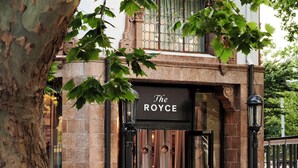 A building with a sign reading 'The Royce' at the entrance, featuring a stone facade and a large tree in the foreground. - The Royce (Melbourne)
