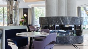 A modern interior with a dining area featuring a round table, purple chairs, and a blue sofa. - The Royce (Melbourne)